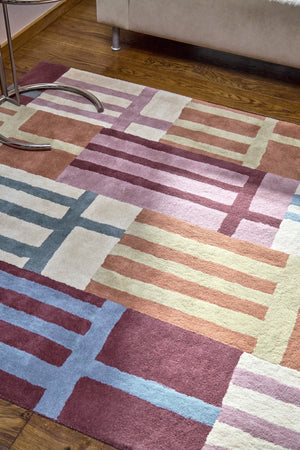 Harlequin Monolith Cinnabar Amber vloerkleed in gebrand oranje, wijnrood en jeansblauw, in een interieur, tweede beeld